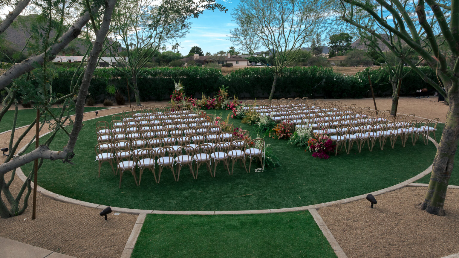Wedding ceremony set on the circular lawn at Andaz Scottsdale Resort and Bungalows, with floral installations and desert trees