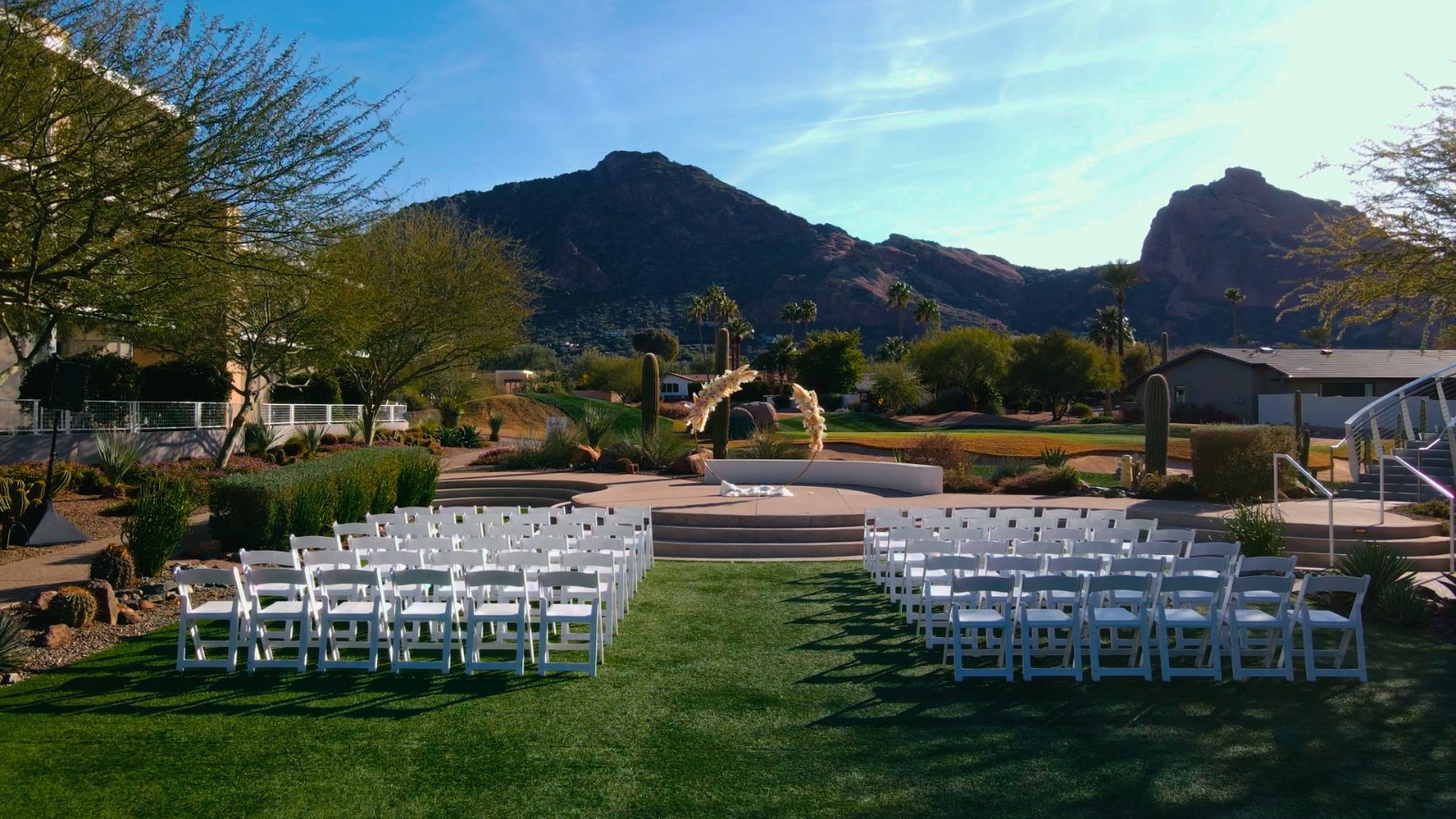 Wedding ceremony set on the Mountain Shadows Lawn at Mountain Shadows Resort in Paradise Valley, with Camelback Mountain behind and the Short Course golf greens visible past the arch
