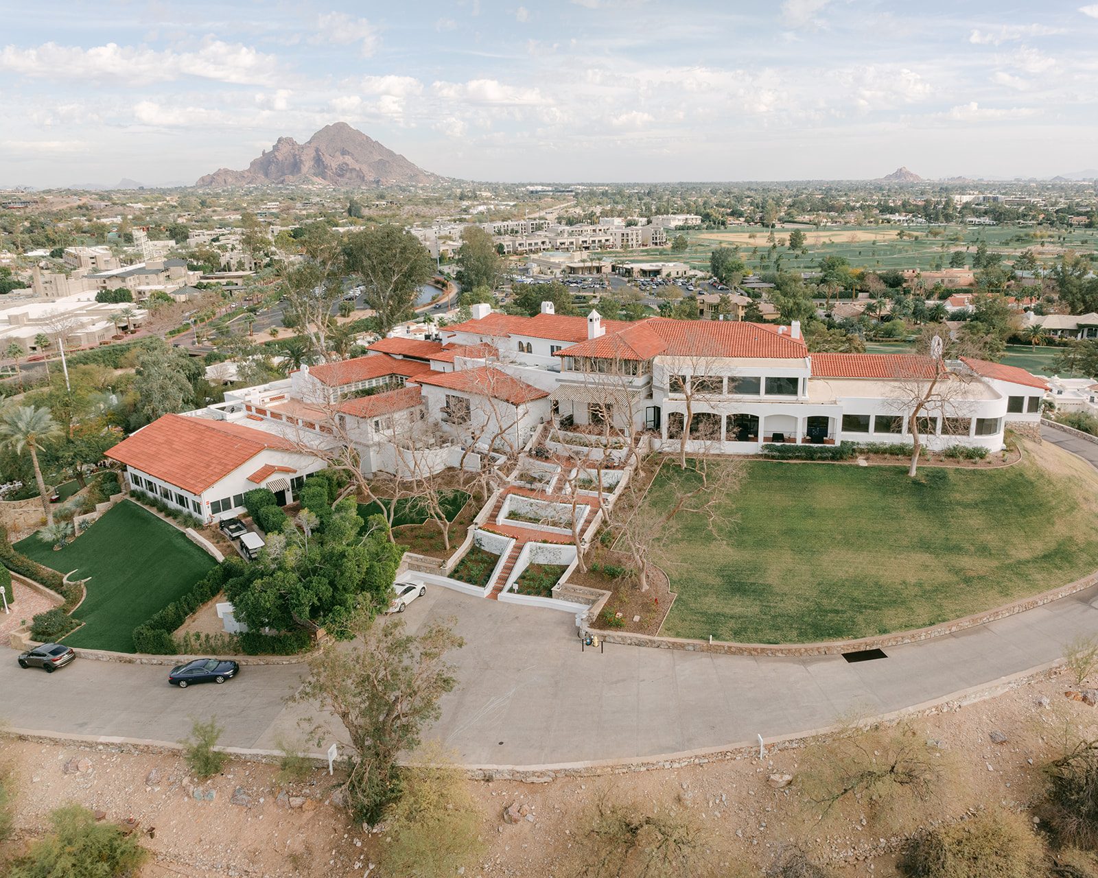Aerial view of Wrigley Mansion on its hilltop in Phoenix, with Camelback Mountain in the distance